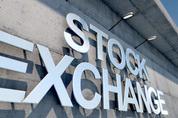 A 3D render of laser cut signage above the entrance to a modern generic stock exchange building composed of exposed concrete in the day time