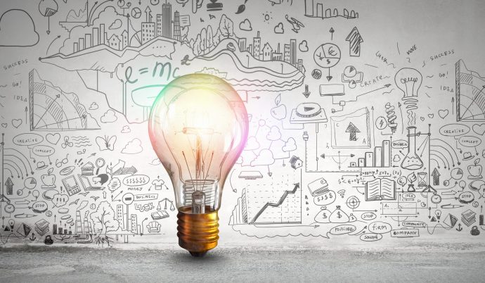 Glass glowing light bulb and business sketched ideas