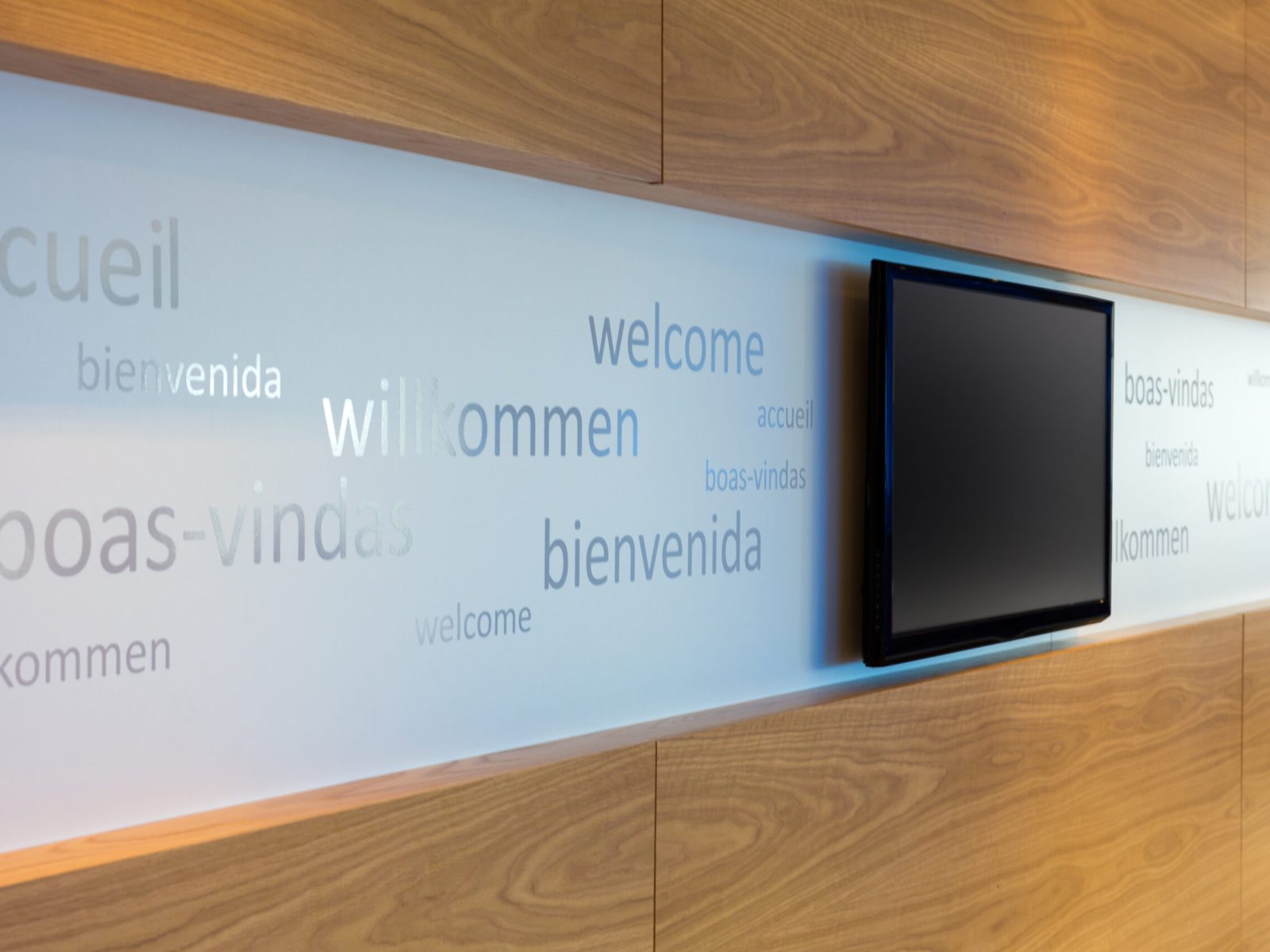 A welcoming office foyer with signage in multiple languages with flat screen TV